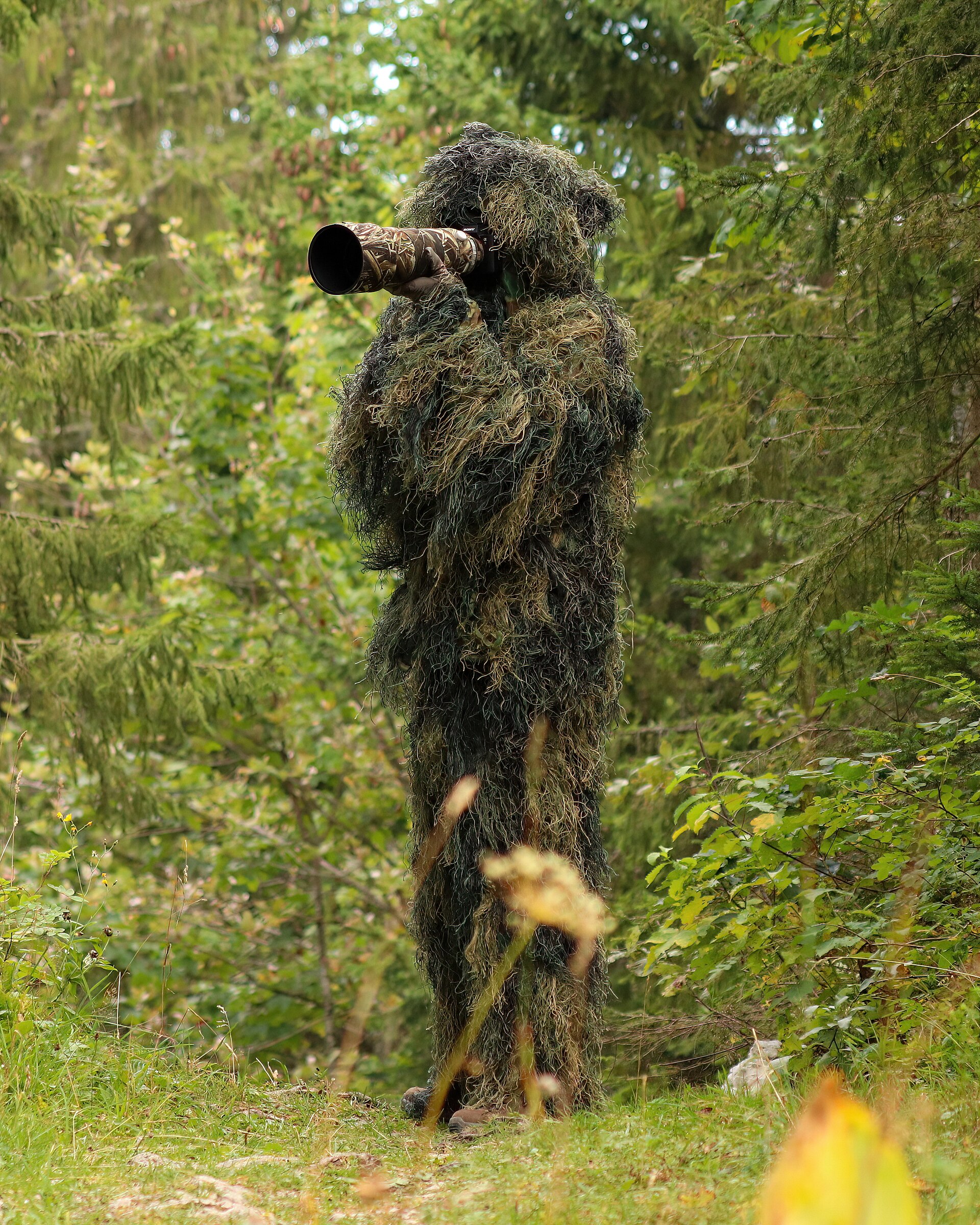 Wildlife Corridors | Good Life News A person in ghillie suit camouflage uses a camera while documenting wildlife, showcasing positive conservation efforts.